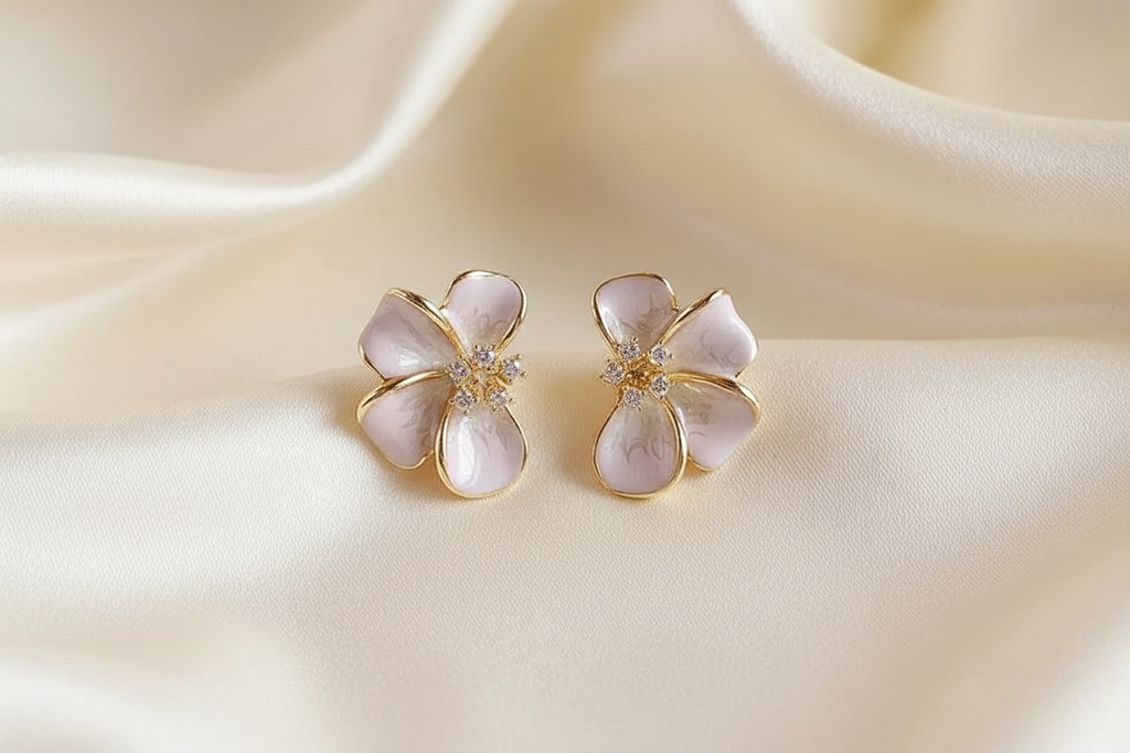 Blush enamel flower earrings on cream silk editorial