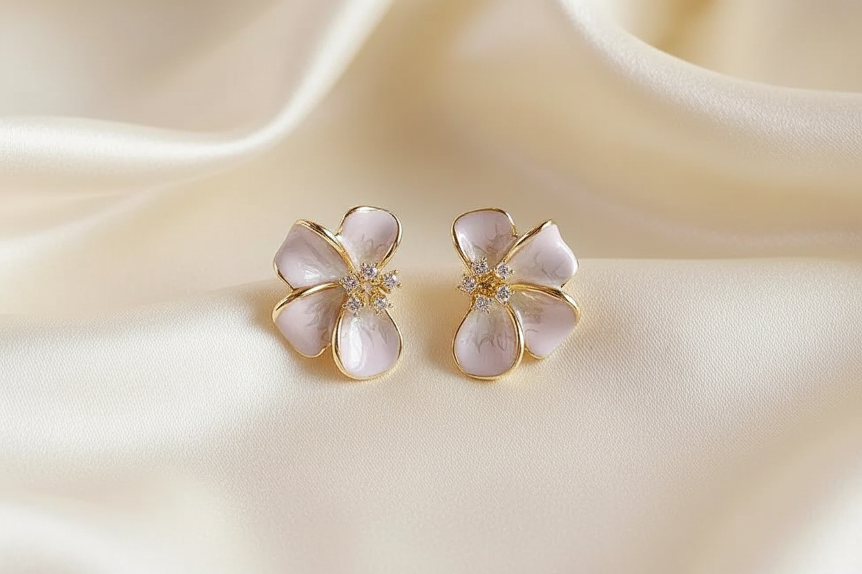 Blush enamel flower earrings on cream silk editorial