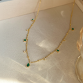 Emerald Constellation Charm Necklace on marble surface