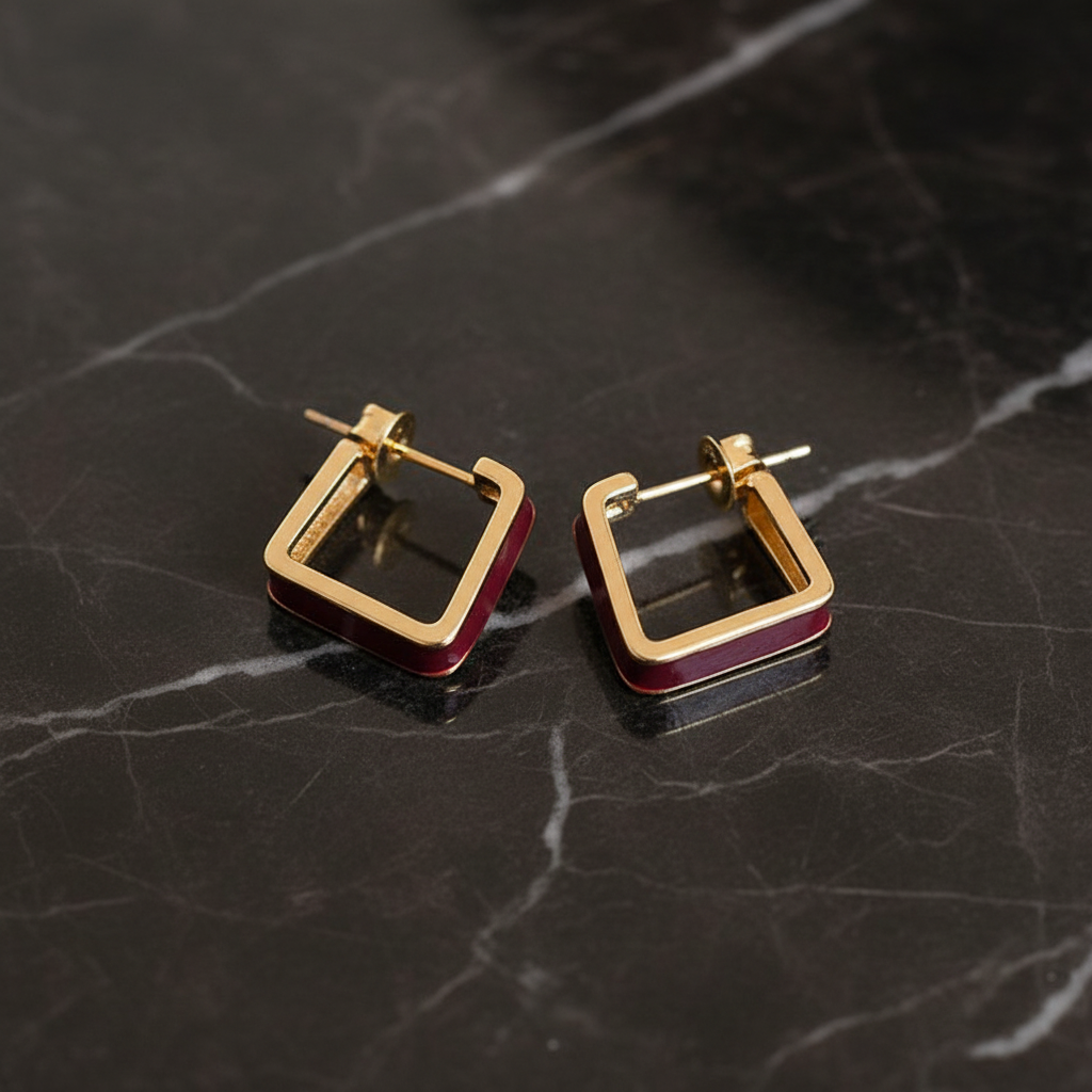Burgundy Enamel Gold Geometric Stud Earrings flat lay on dark marble