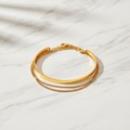 Gold cuff bangle and chain bracelet set on white marble