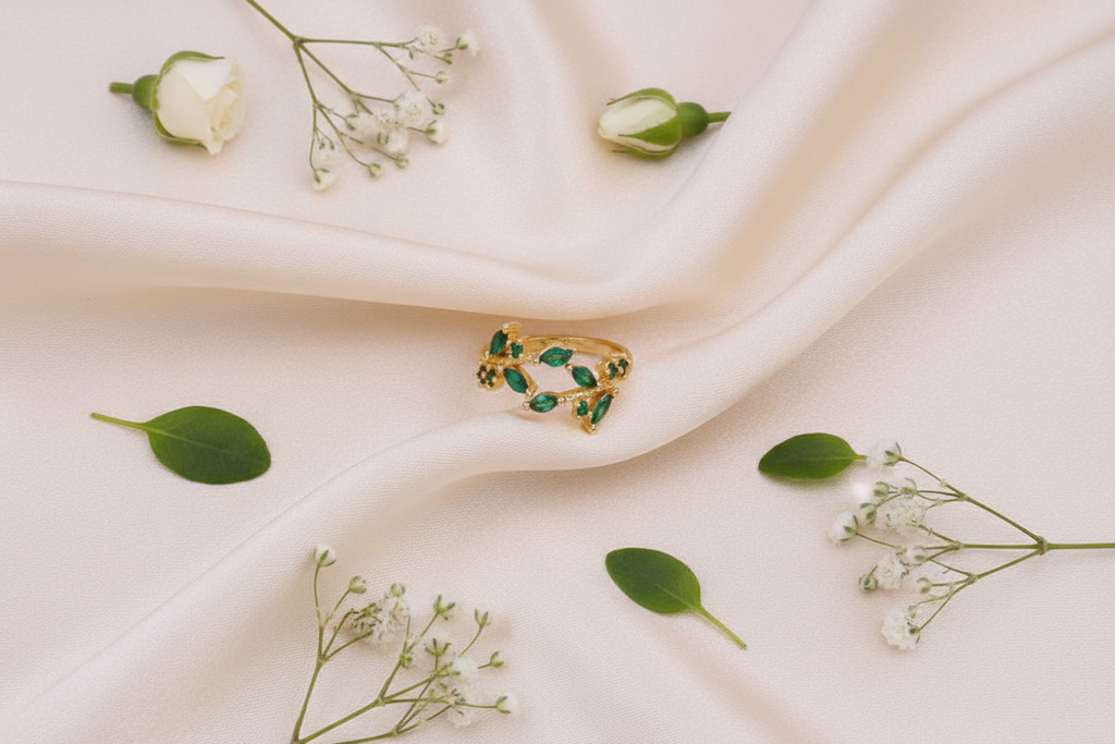 Gold emerald leaf ring on cream silk editorial