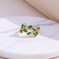 Gold emerald green leaf ring on white marble