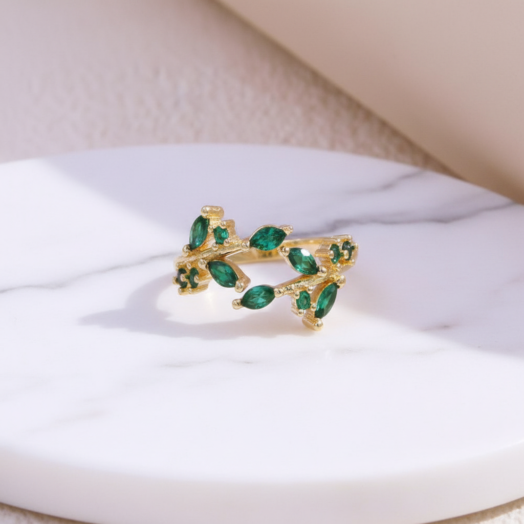 Gold emerald green leaf ring on white marble